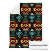 Folded black blanket with multicolor geometric medallions and stacked-triangle borders