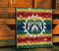 Rainbow quilt with white thunderbird center emblem and geometric symbols, square pattern