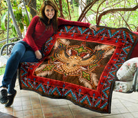 Folded red Native-style quilt with turquoise patterned border and owl medallion center