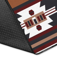 Rug corner close-up: brown, black, and red geometric pattern with white border trim