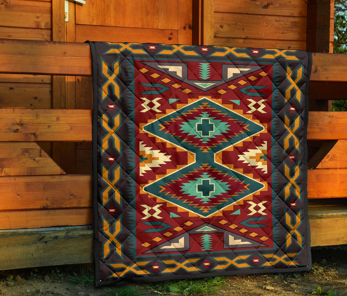 Native American quilt draped on wooden porch with geometric diamond motifs in red and teal