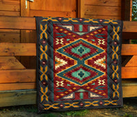 Native American quilt draped on wooden porch with geometric diamond motifs in red and teal