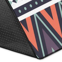 Corner view of colorful tribal area rug: dark base, orange and teal zigzags, dotted texture