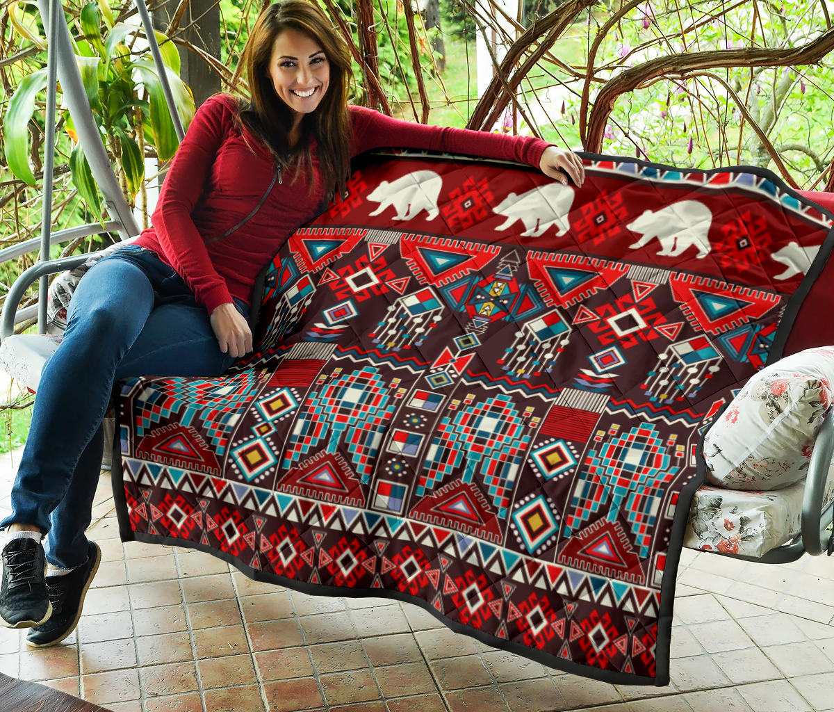 Quilt held on patio: white bear silhouettes over red and multicolor tribal geometric pattern