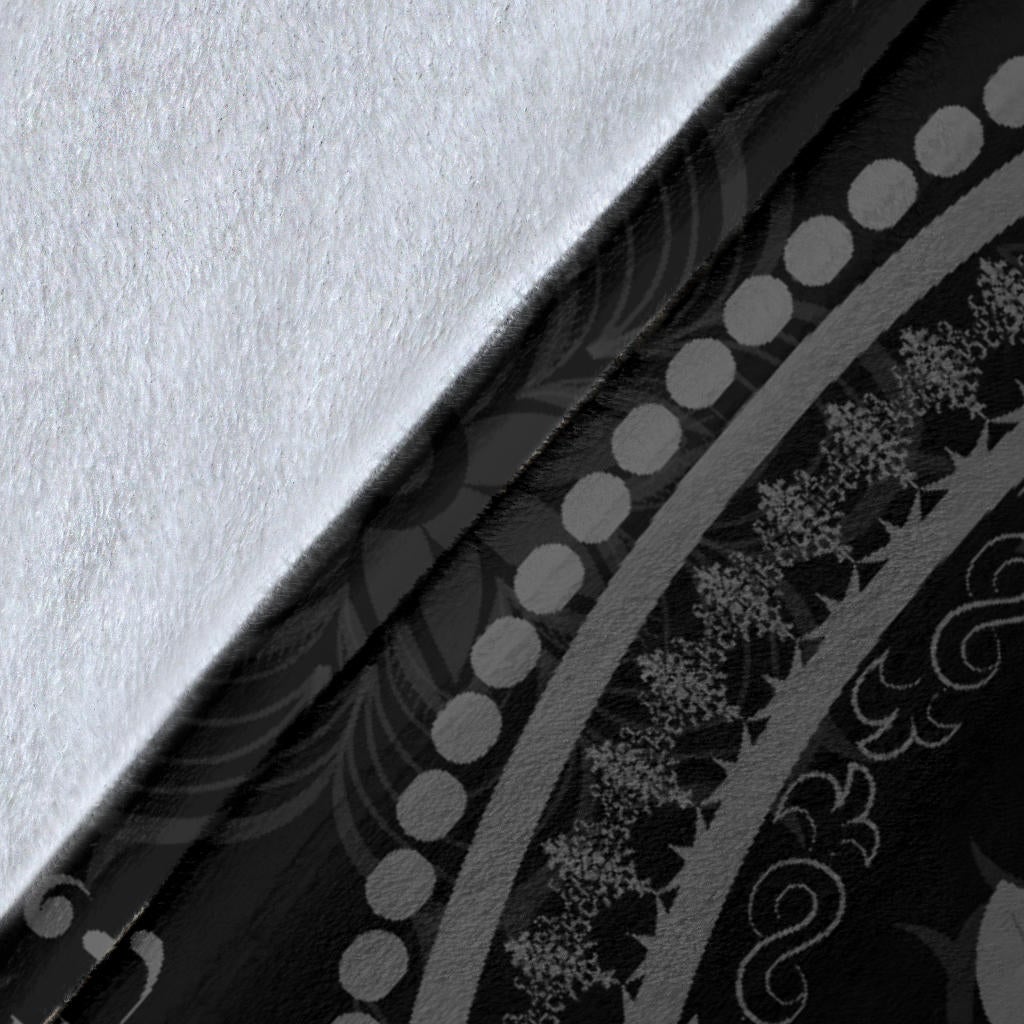 Black blanket corner close-up with gray decorative border and repeating pattern