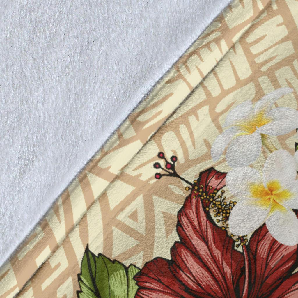 Close-up of beige blanket fabric with fish hook artwork and red hibiscus flower detail