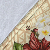 Close-up of beige blanket fabric with fish hook artwork and red hibiscus flower detail