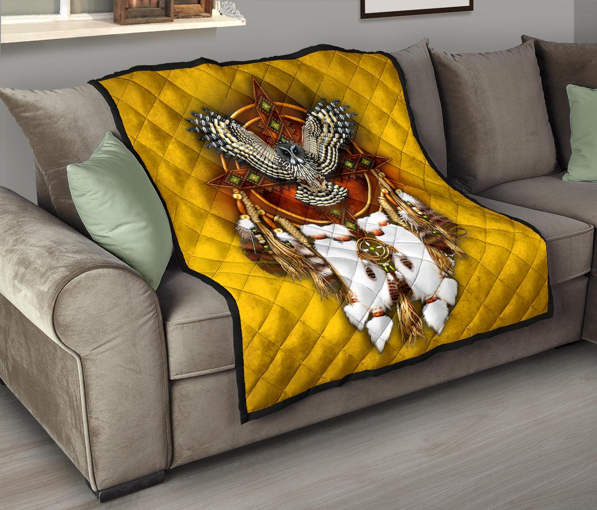 Yellow quilt blanket on gray couch with owl/dreamcatcher design, fringed tassels, black trim