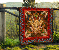 Quilt hanging outdoors: red frame with centered owl design and multicolor geometric edge