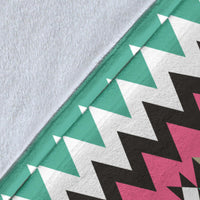 Close-up of turquoise blanket fabric with white triangles and pink/black zigzag