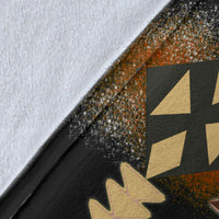 Close-up of geometric blanket fabric, black base with brown and gold motifs