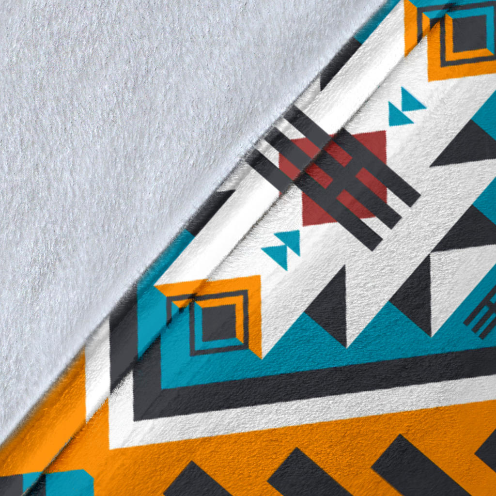 Close-up of Aztec geometric blanket fabric, teal and orange stripes with navy shapes on white