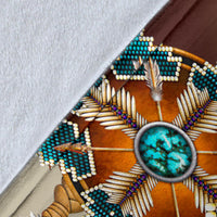 Close-up of wolf blanket fabric edge with turquoise circular bead detail and feather lines