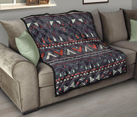 Native quilt on gray sofa: dark elephants and tribal bands in red, cream, and teal accents.