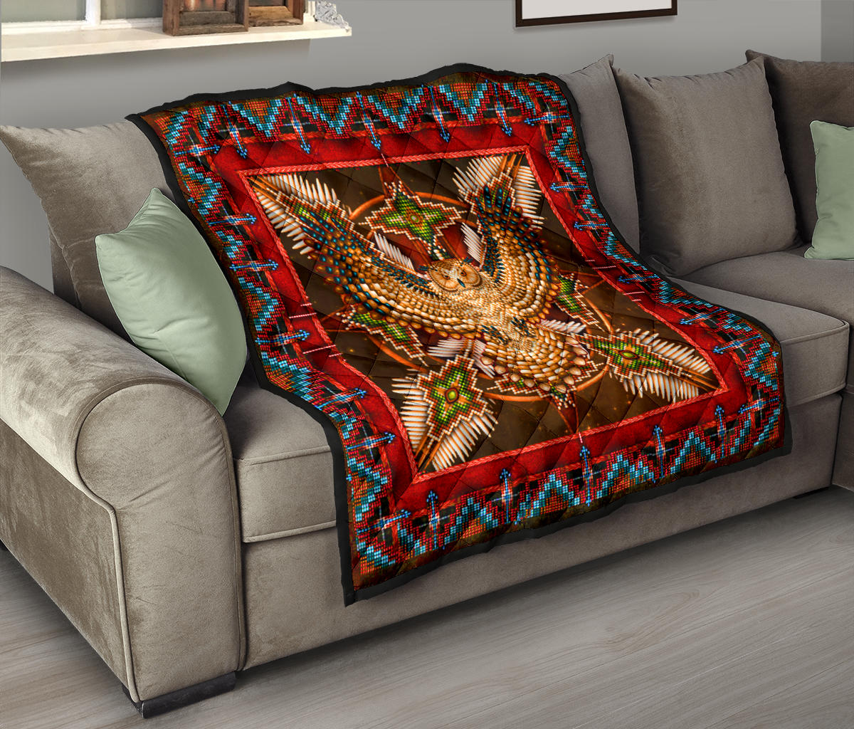 Quilt draped on sofa with red border, turquoise trim, and owl mandala centerpiece
