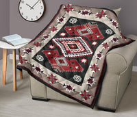 Quilt over beige couch arm featuring red diamond medallions and star print border.