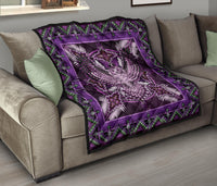 Purple Native American mandala quilt folded on a couch, with green geometric edge border