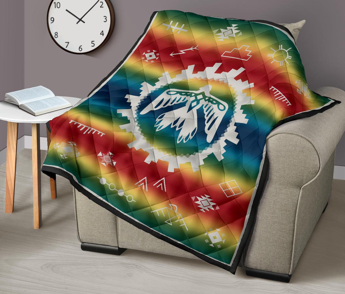 Rainbow quilt blanket on an armchair with white thunderbird emblem and geometric pattern