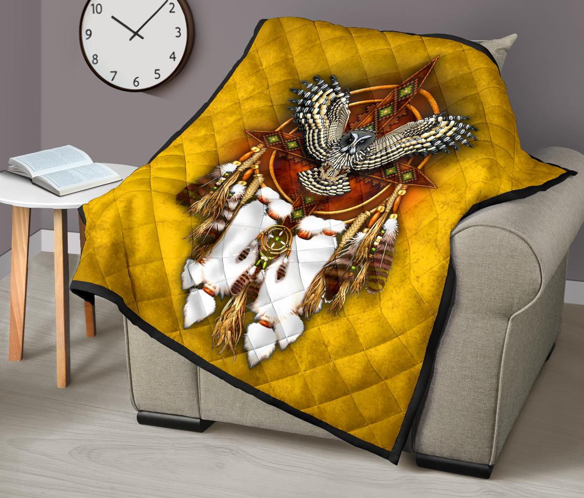 Yellow owl quilt over gray sofa with dreamcatcher center, white feathers, black-edged border