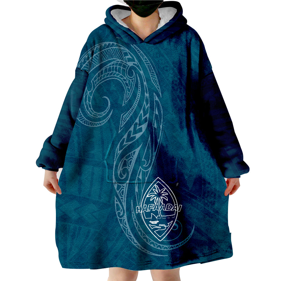 Dark teal wearable blanket hoodie with hood, oversized front pocket, and crest graphic