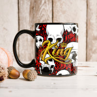 Black ceramic mug with skull and roses graphic on front, gold crown lettering