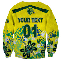 Yellow sweatshirt with green cricket crest, 'YOUR TEXT 01' print and Aboriginal-style hands