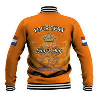 Orange baseball jacket back with crown graphic, 'Happy King's Day' text, striped hem.
