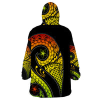 Wearable blanket hoodie, back view with black base and yellow-green tribal pattern and eyes
