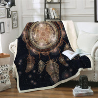 Black galaxy dreamcatcher blanket with gold web and feather prints, on bed