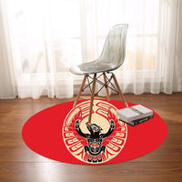 Red round thunderbird rug with black, cream, and beige tribal design under a chair
