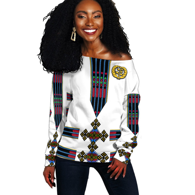 White off-shoulder sweater with colorful Eritrea-style geometric print and gold emblem