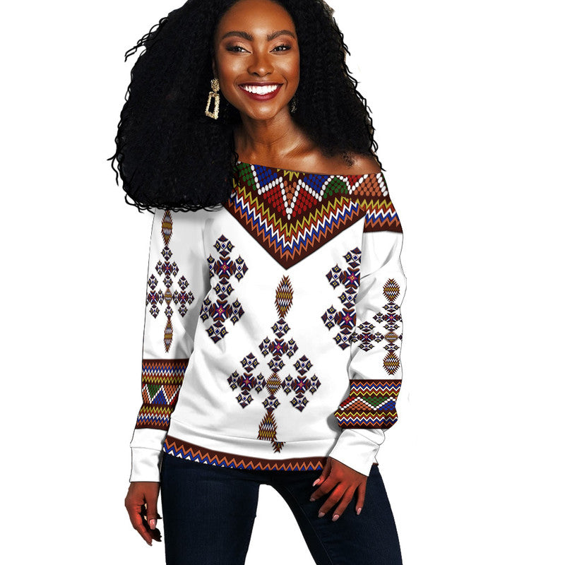 Women off-shoulder sweater, white with colorful Ethiopian geometric knit pattern