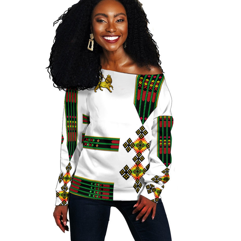 White off-shoulder sweater with Ethiopian lion & green/red geometric print