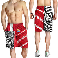 Red men’s swim shorts with elastic waist, white chevrons, black tribal print, small crest